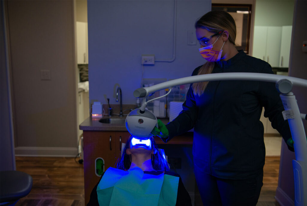 patient recieving teeth whitening treatment via a LED light