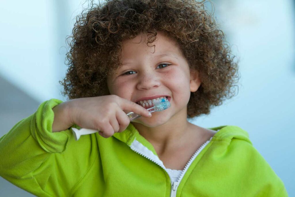 smiling little kid brushing their teeth
